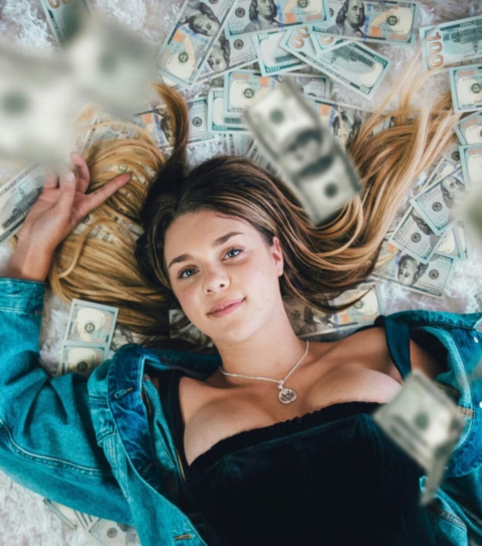 Credit: Andre Sebastian – Unsplash Woman lying in a pile of money