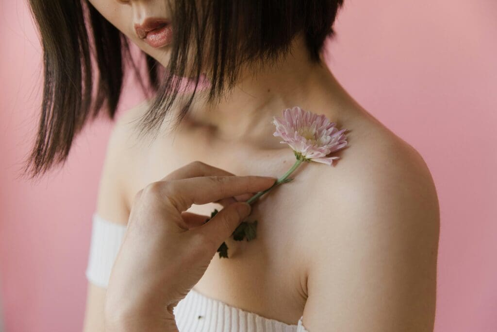 A woman holding a flower;
Image: Mart Production, Pexels