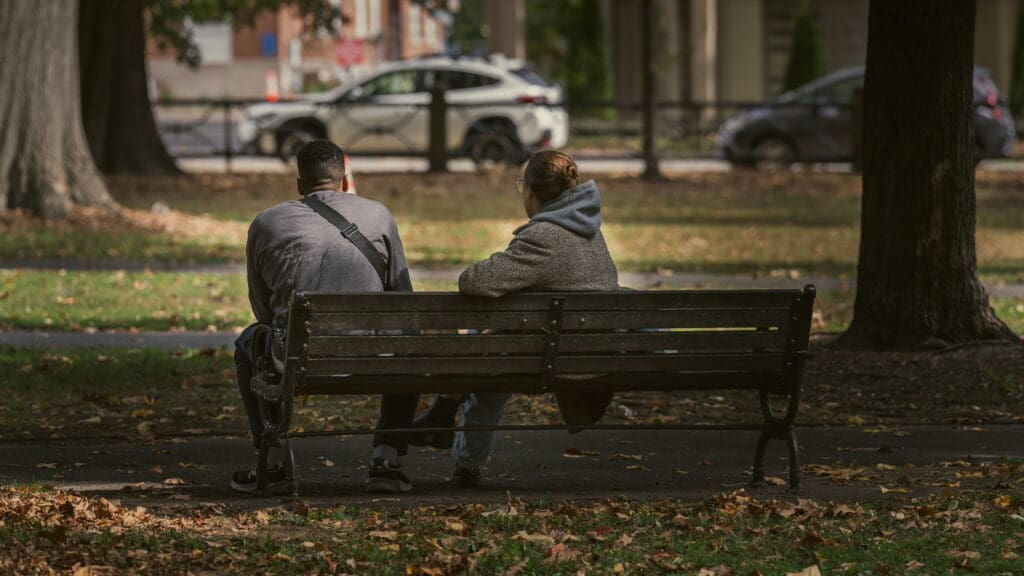 A couple sits together on a park bench. Image: Martin Podsiad / Unsplash
