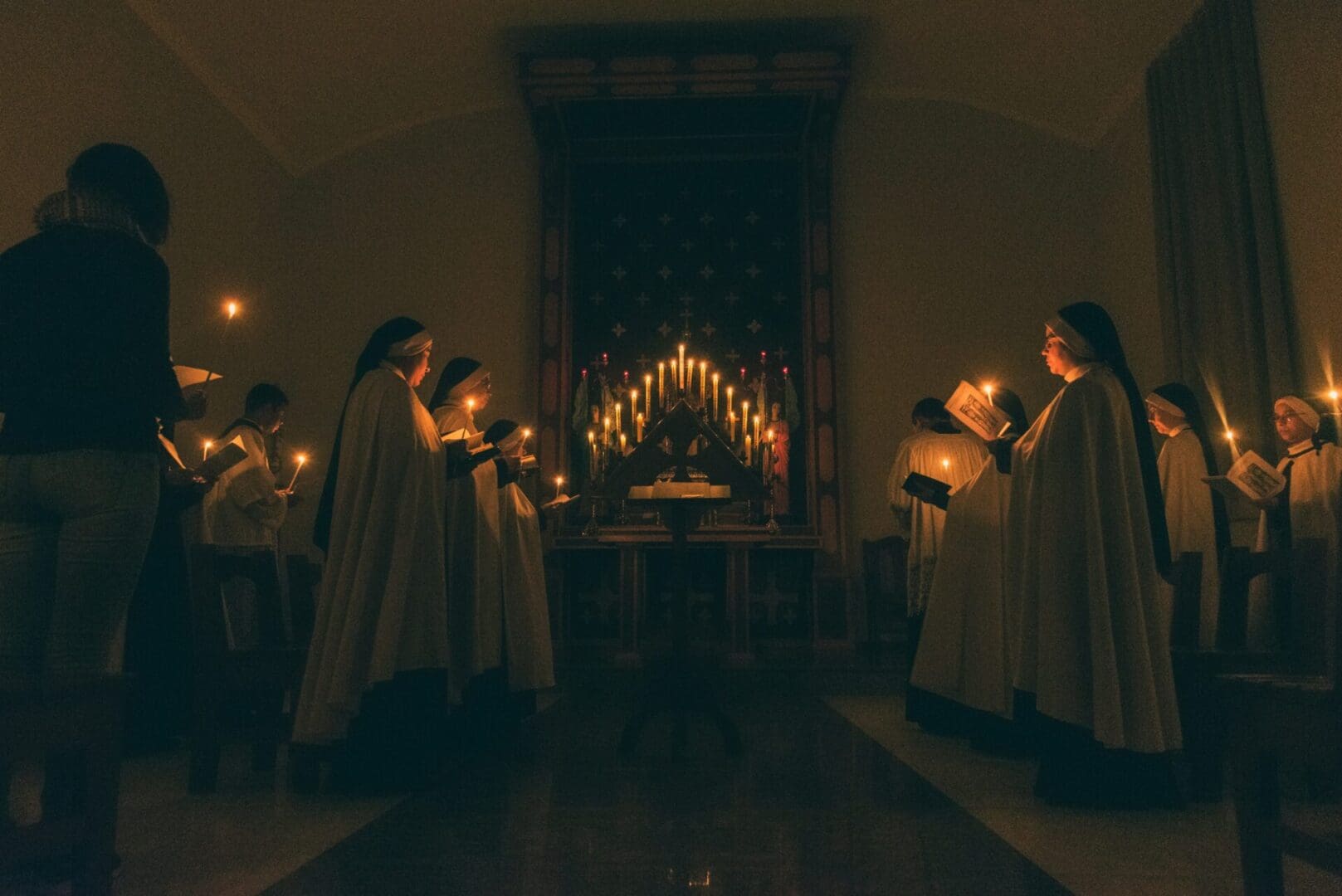 Nuns Featured Image Nuns holding hymn books in candlelight