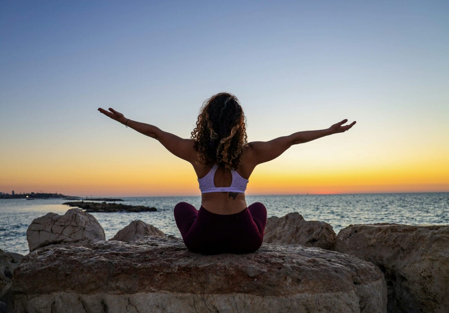 Woman with her arms in the air in front of a sunrise